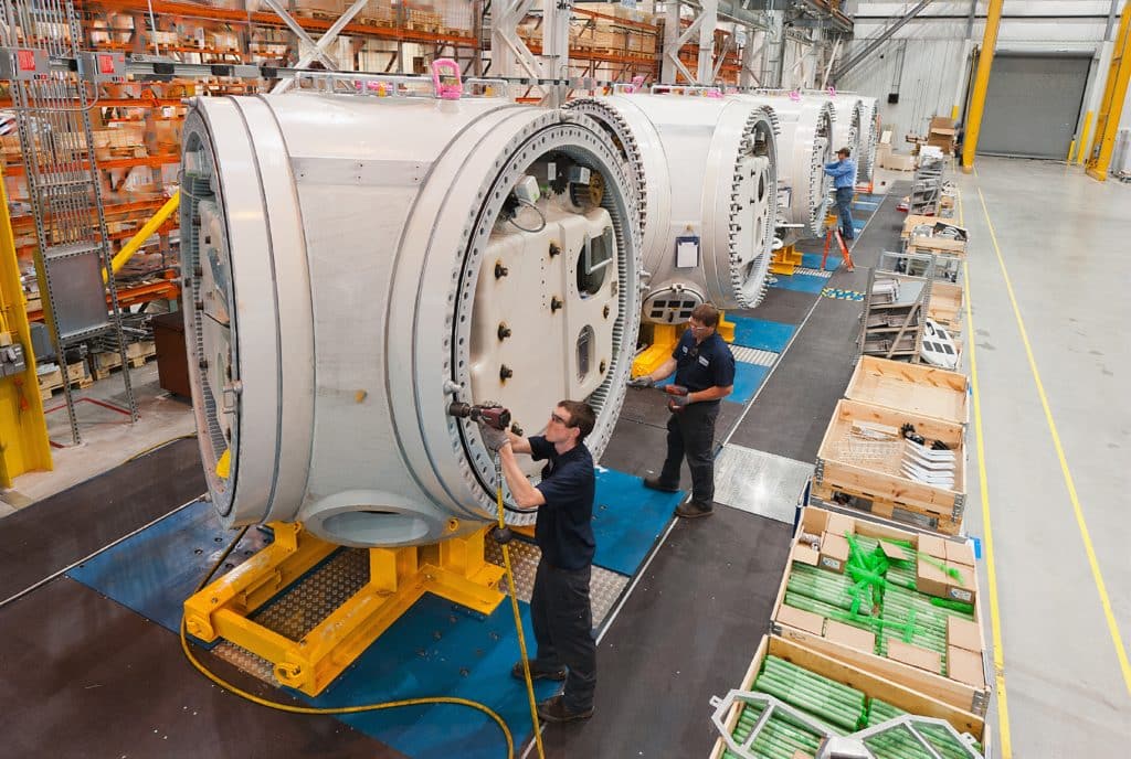 man in blue jacket standing beside gray and blue industrial machine